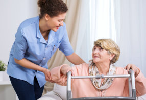 caregiver helping a senior woman to stand up