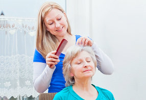 young woman combing the hair of a senior woman