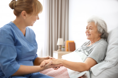 caregiver holding the hand of a senior woman
