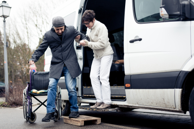 caregiver assisting senior man to go out on the van